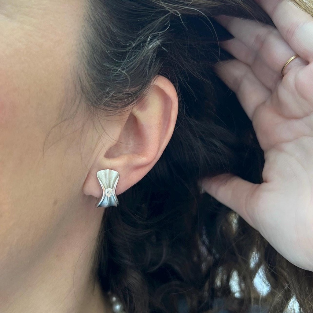 Pendiente Lazos con un brillante central en cada uno, Oro Blanco  de 18 kilates cierre Omega